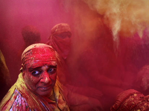 Hindu men from the village of Nangaon, India, are covered in colored powder as they sit on the floor during prayers at the Ladali, or Radha temple, before the procession for the Lathmar Holi festival in the legendary hometown of Radha, consort of Hindu go 
