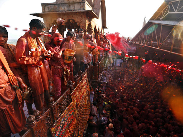 Hindu men throw and spray colored water on men from the village of Nangaon, India, as they sit on the floor during prayers at the Ladali, or Radha temple, before the procession for the Lathmar Holi festival in the legendary hometown of Radha, consort of H 