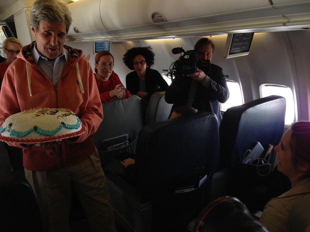 U.S. Secretary of State John Kerry presents a birthday cake to CBS News State Department correspondent Margaret Brennan, as they marked her birthday while flying from Kabul, Afghanistan, to Paris, France, March 26, 2013. 