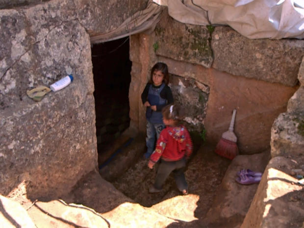 Young Syrian girls stand outside the entrance to an underground dwelling in Roman ruins 