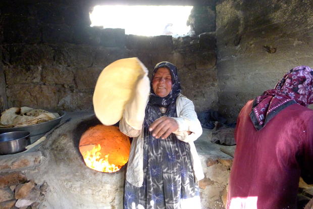A Syrian woman bakes bread in a earthenware oven in her underground dwelling  