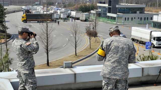 U.S. soldiers take pictures as South Korean trucks turn back at a border crossing in Paju 