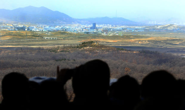 Visitors look over North-South Korea industrial complex in Kaesong, North Korea, through binoculars at Dora Observation Post in demilitarized zone (DMZ) near border village of Panmunjom, in Paju, South Korea, on April 9, 2013 