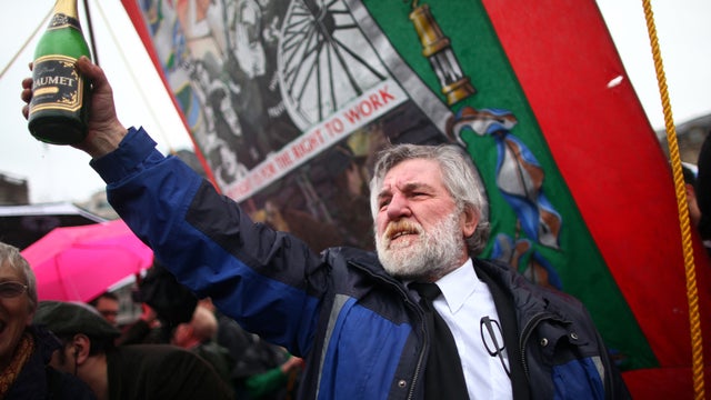 A former mine worker raises a bottle of Champagne during a party held in Trafalgar Square April 13, 2013, in London following the death of former British Prime Minister Margaret Thatcher. 