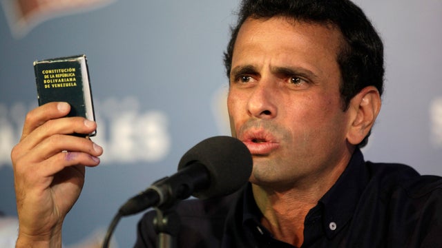 Opposition leader Henrique Capriles holds-up copy of Venezuela's constitution during news conference in Caracas, Venezuela, late Thursday, April 18, 2013. 