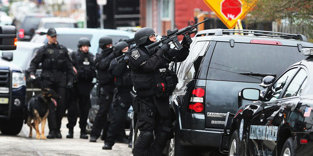 WATERTOWN, MA - APRIL 19: A Boston SWAT team member takes up as posistion as they search for 19-year-old bombing suspect Dzhokhar A. Tsarnaev on April 19, 2013 in Watertown, Massachusetts. After a car chase and shoot out with police, one suspect in the Bo 