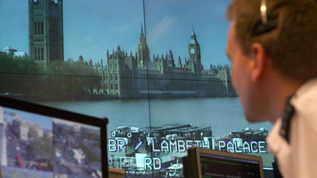 A police officer watches banks of television monitors 