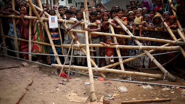 Curious onlookers and relatives of missing victims watch from behind makeshift fence as workers dislodge parts of the garment factory building that collapsed in Savar, near Dhaka, Bangladesh 