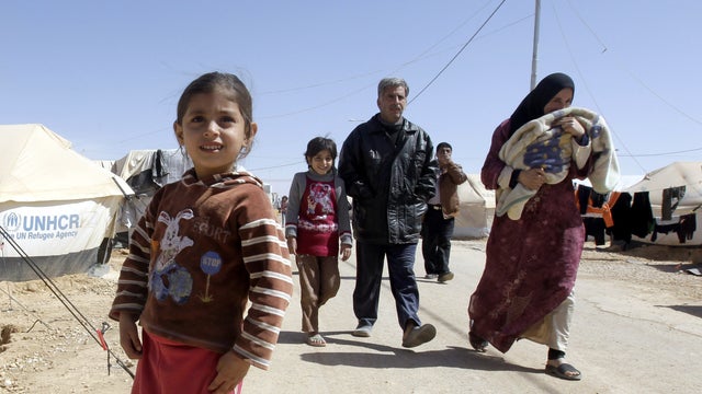 A Syrian family walks amid tents at the Zaatari refugee camp 