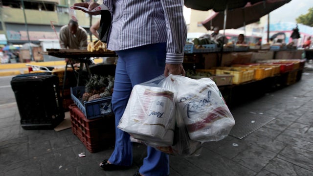 A woman who just bought toilet paper at a grocery store reads her receipt 
