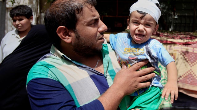 Ali Arar holds his one-year-old son, who was wounded in a car bomb attack 