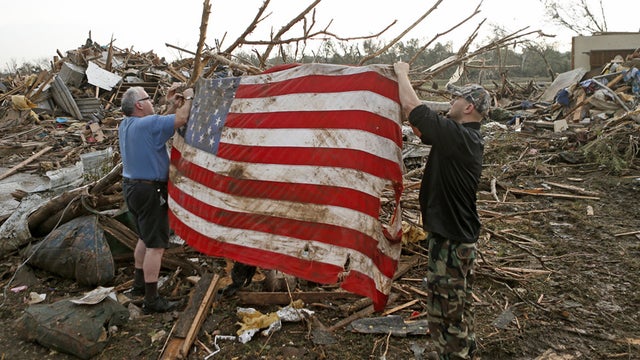 Clark Gardner, at left, and another man place an American flag on debris in a neighborhood off of Telephone Road in Moore, Okla., after a tornado moved through the area on Monday, May 20, 2013. 
