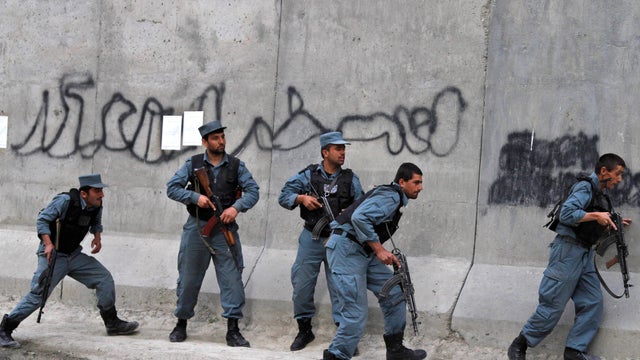 Afghan police take cover during a gun battle which immediately followed a suicide attack 