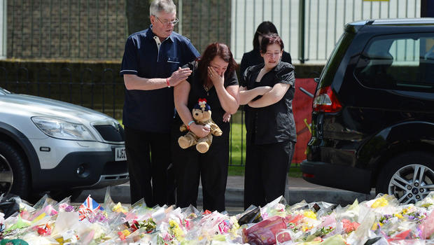 Lyn Rigby, mother of Drummer Lee Rigby, holding a teddy bear joins other family members as they look at floral tributes outside Woolwich Barracks left by well wishers as they visited the scene of the 25-year-old soldier's murder in Woolwich, south-east London, Sunday May 26, 2013. 