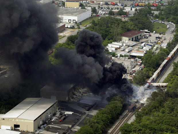 A fire burns at the site of a CSX freight train derailment, Tuesday, May 28, 2013, in Rosedale, Md., where fire officials say the train crashed into a trash truck, causing an explosion that rattled homes at least a half-mile away and collapsed nearby buildings, setting them on fire. 