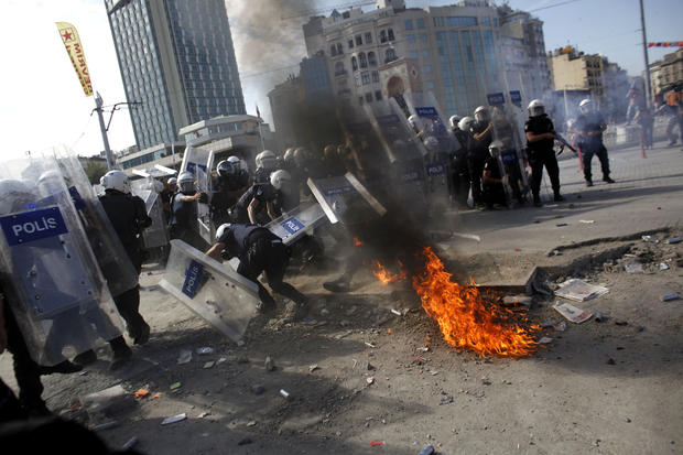 Riot police take cover as a molotov cocktail explodes in front of them during clashes in Taksim Square 