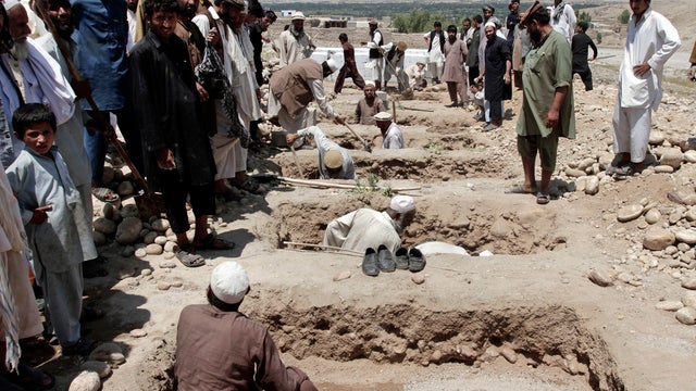 Afghan men prepare graves for seven civilians, including four women and two children, killed when their vehicle was hit by a roadside bomb 