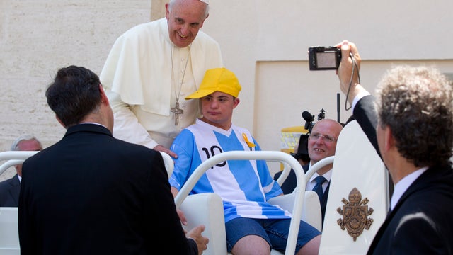 Pope Francis smiles as Alberto di Tullio, from Boiano, near Naples, Italy, sits in the pope's seat of his open-top car at the end of his weekly general audience in St. Peter's Square at the Vatican 