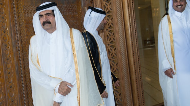 Qatari Emir Sheikh Hamad bin Khalifa al-Thani (L) and his son Qatari Crown Prince Sheikh Tamim bin Hamad bin Khalifa al-Thani (R) await France's President Francois Hollande prior to a welcoming ceremony at the Diwan Emiri. 