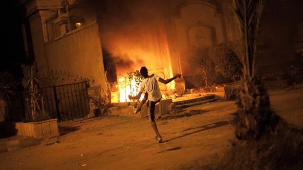 An Egyptian protester attacks Muslim Brotherhood headquarters in Muqattam district in Cairo, Sunday, June 30, 2013.  