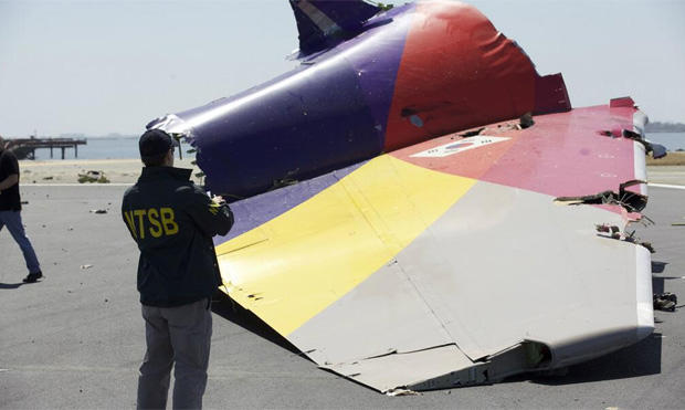 An NTSB officer examines a piece of Asian Airlines Flight 214 after it crash landed on a runway at San Francisco International Airport. 