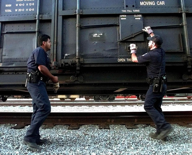U.S. Customs agents prepare to open a train car north of Laredo, Texas, on June 28, 1999. The intense manhunt for the railroad killer had intensified train car searches. 