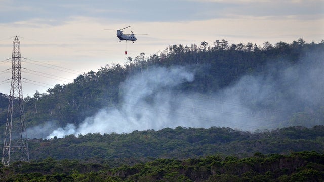 A US military helicopter flies on a fire fighting operation after a US military helicopter crashed on a mountain in Camp Hansen in Ginoza village in Okinawa on August 5, 2013. 