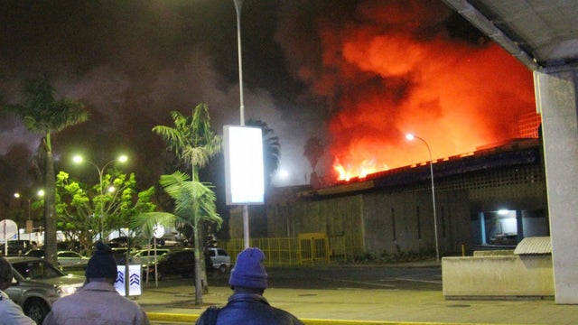 People watch large blaze raging at Jomo Kenyatta International Airport in Nairobi, Kenya, early Tuesday, Aug. 7, 2013 