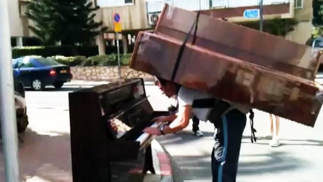 Man plays piano with a piano on his back 