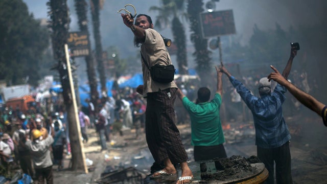 A supporter of ousted Islamist President Mohammed Morsi shoots a slingshot against Egyptian security forces during clashes in Rabaah Al-Adawiya in Cairo's Nasr City district, Egypt, Aug. 14, 2013.  