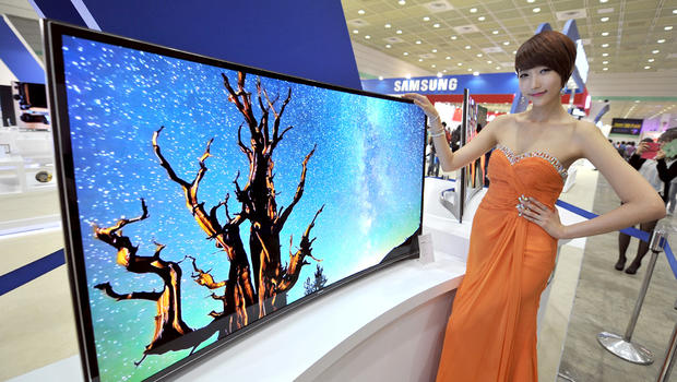 A South Korean model poses with a 55-inch curved OLED TV of Samsung Electronics during an IT show in Seoul on May 21, 2013. 