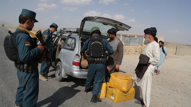 Afghan police search passengers at a checkpoint where Taliban militants kidnapped a female Afghan member of parliament 