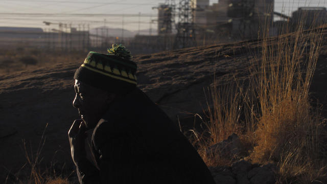 A South African miner looks over the area where, a year ago, police opened fire on striking platinum miners killing 34 and injuring 78 