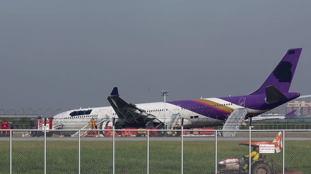 An airport worker drives a cart by a damaged Thai Airways Airbus A330-300  