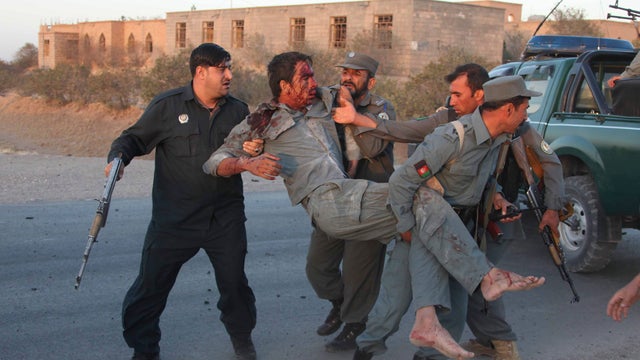 Afghan security personnel assist an injured police officer after a suicide car bombing and a gunfight near the U.S. Consulate in Herat 