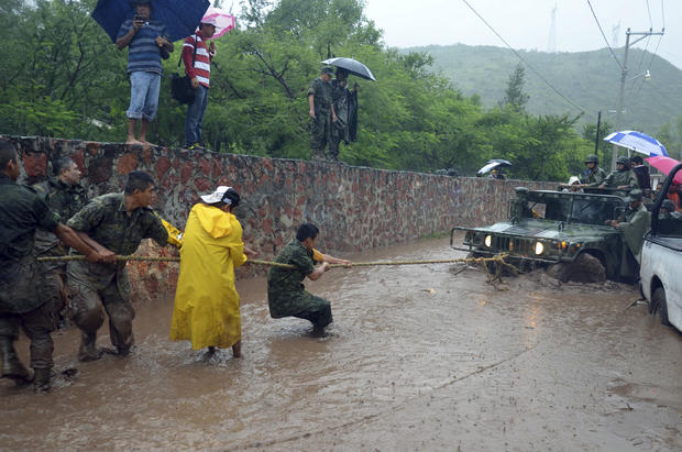 Army soldiers work to try to get their vehicle out of a flooded portion of a road caused by Tropical Storm Manuel in the city of Chilpancingo, Mexico, Sunday Sept. 15, 2013. In the southern Pacific Coast state of Guerrero, rains unleashed by Manuel resulted in the deaths of six people when their SUV lost control on a highway headed for the tourist resort of Acapulco. Another five people died in landslides in Guerrero and Puebla states, while the collapse of a fence killed another person in Acapulco. 