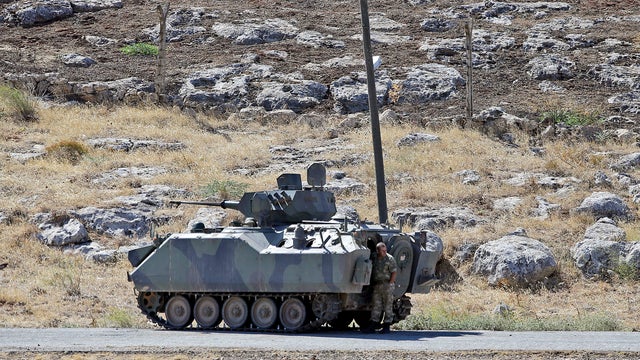 A Turkish soldier stands by a tank as he patrols the border with Syria 