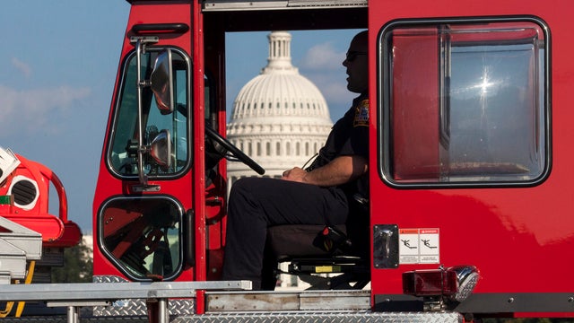 A firefighter sits in a firetruck near the scene on the National Mall in Washington where a man set himself on fire Oct. 4, 2013. 