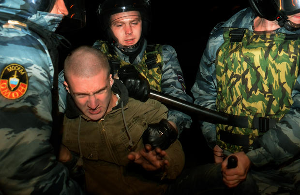 Russian riot police escort a man detained during mass rioting in the southern Biryulyovo district of Moscow 