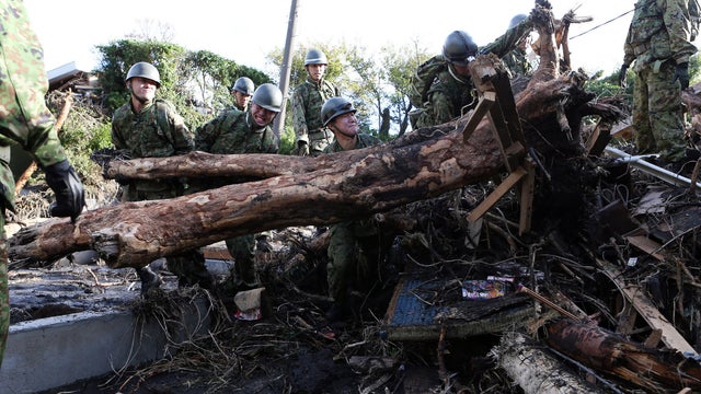 Japanese soldiers remove debris to search for survivors after a landslide buried houses on Oshima island 