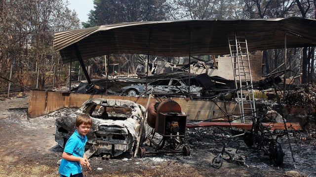 Lyndon Dunlop walks in the backyard of of his grandparent's home of 41 years destroyed by bushfire 