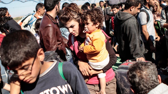A Syrian refugee holds her child as she and others are refused entry from northeastern Syria into northern Iraq by the Kurdistan regional government based in northern Iraq Oct. 23, 2013. 