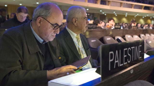 The Palestinian Ambassador to UNESCO, Elias Sanbar, left, checks his tablet during a session of the UNESCO General Conference 