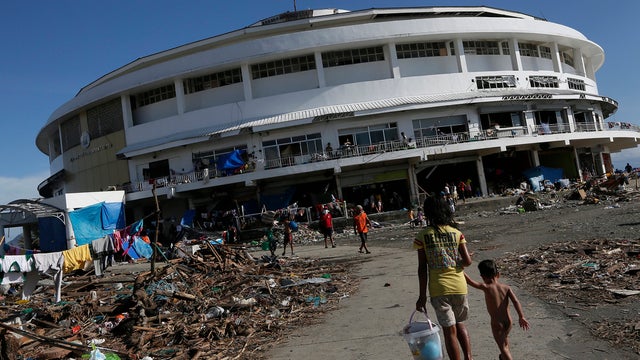 A young girl walks her brother to the Tacloban City Convention Center, known as the Astrodome 