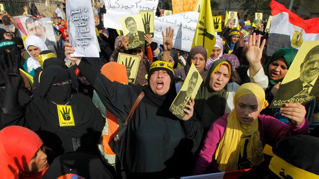 Supporters of Egypt's ousted President Mohammed Morsi raise his posters and their hands with four raised fingers, which has become a symbol of the Rabaah al-Adawiya mosque, where Morsi supporters had held a sit-in for weeks that was violently dispersed in 