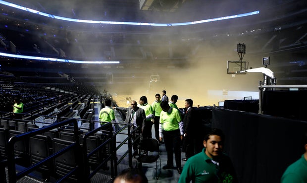 People leave as smoke engulfs the basketball court during a regular season NBA match between the Minnesota Timberwolves and the San Antonio Spurs in Mexico City 