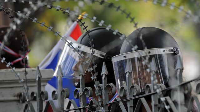 Thai anti-government protesters watch police positions from outside the besieged Government House compound during an ongoing protest in Bangkok 