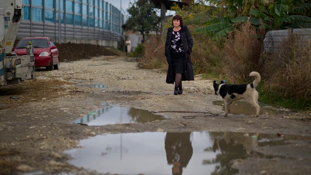 Irina Kharchenko walks in the yard of her house beside the screen separating her property from a federal highway in the village of Vesyoloye outside Sochi 