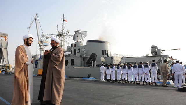 Iranian clerics stand in front of an Iranian warship during naval maneuvers in the Gulf 