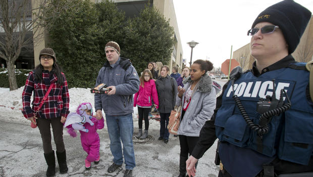 A Howard County police officer escorts visitors from The Mall in Columbia Jan. 25, 2014, in Columbia, Md., to a nearby parking lot following a shooting at the mall. 